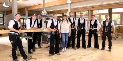 team von holzbau h&ouml;fer in traditioneller zimmerer-kleidung in werkstatt